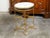 An Italian gilt metal side table from the mid 20th century, with white marble top and in-curving accents. Created in Italy...