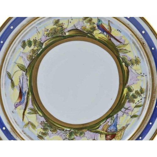 Finely decorated porcelain saucer, notable for its colorful and intricate hand-painted design. The rim is adorned with a...