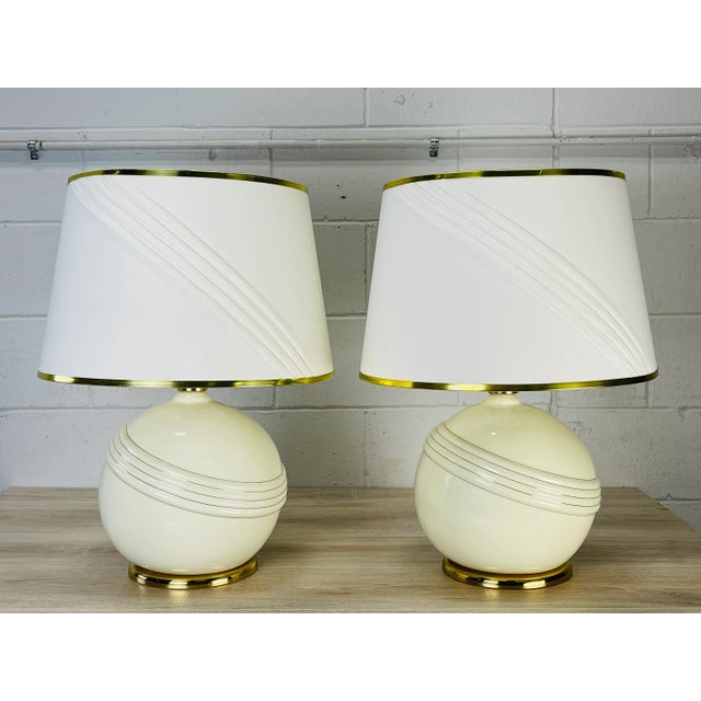 Vintage early 1970s round cream and gold accented pair of table lamps. The lamps come with the original shades. The lamps...