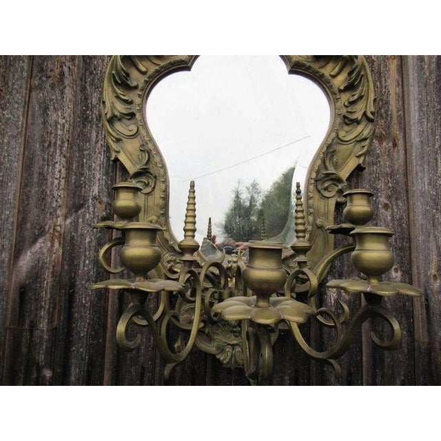 A 19th century heavy gilt brass mirror with five branch candelabra, the central foliate pediment flanked by scrolled leaf...