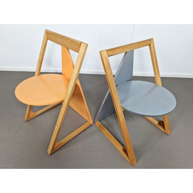 A pair of postmodern triangle shaped chairs in different color finishes and with a sleightly different backrest. Probably...