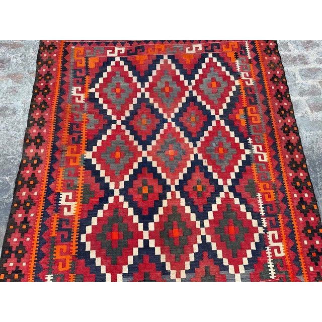 This vintage Afghan flat weave kilim rug, handmade in the 1970s in Maimana Village, Afghanistan, features a classic...