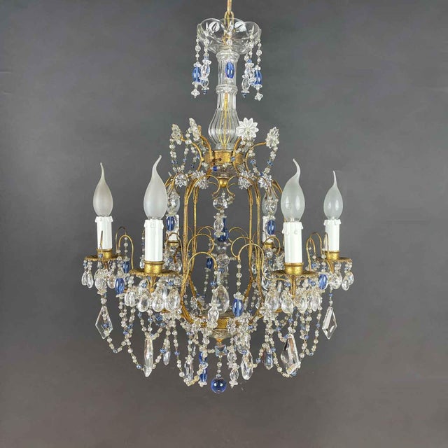 A gilded iron and blue crystal chandelier dating back to 1950, featuring an elegant and romantic design. This six-light...