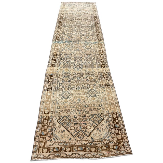 An elegant antique runner with a beautifully faded palette and an intricate geometric design. The warm beige field is...