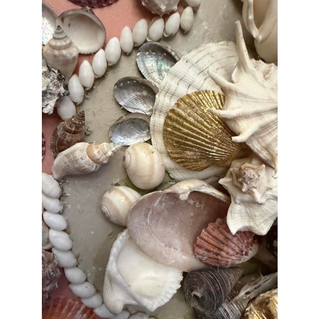 Shell embellished wall plaque on a salmon background. Several gold leafed shells add a layer of luxurious texture.Unique...