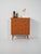 Teak chest of drawers with four drawers, double oval recessed handles, and obliquely turned legs. Soft lines, warm grain....