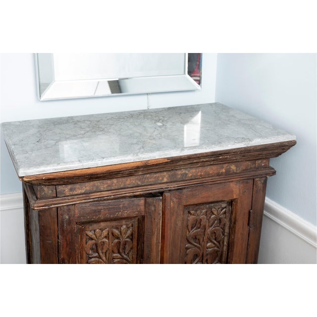 An antique traditional Indonesian hand carved cabinet with intricately floral carved doors and apron and two doors with...