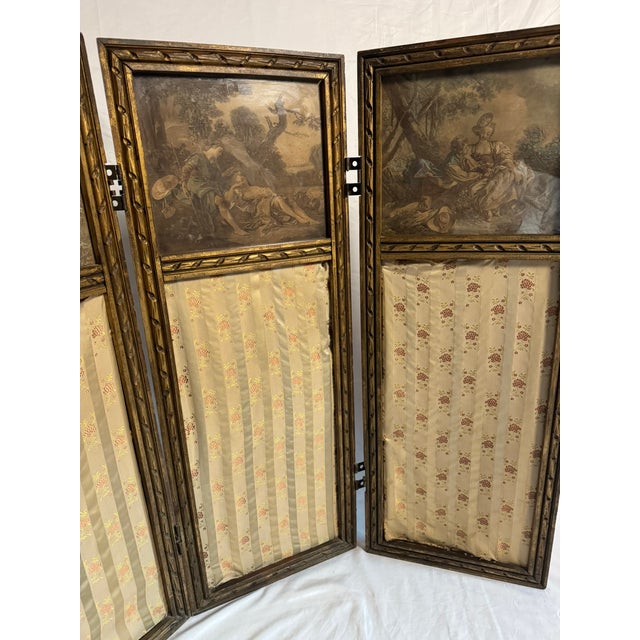 This is a petite antique French folding screen in a Louis XVI style from the 1900's — three hinged giltwood leaves, each...