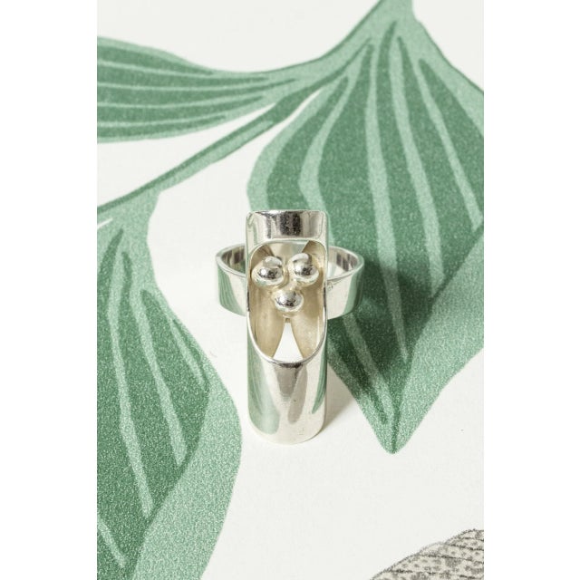 Cool silver ring by Elis Kauppi, with a silver cylinder in whistle form. Cutout form showing silver balls inside. This...