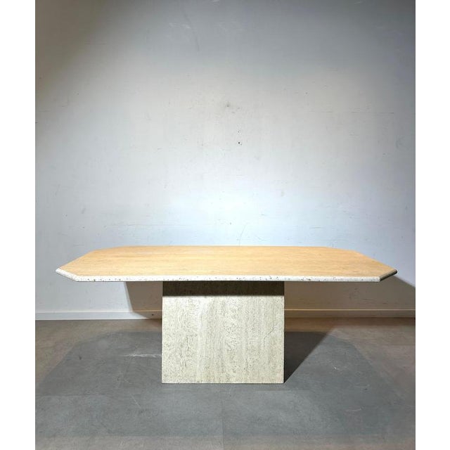 Elegant vintage dining table featuring a solid travertine base combined with a rectangular travertine top with softly...