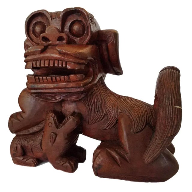 A unique pair of vintage hand carved wood foo dogs statues made of a very dark stained wood. Measurements 9” H x 10” W X...