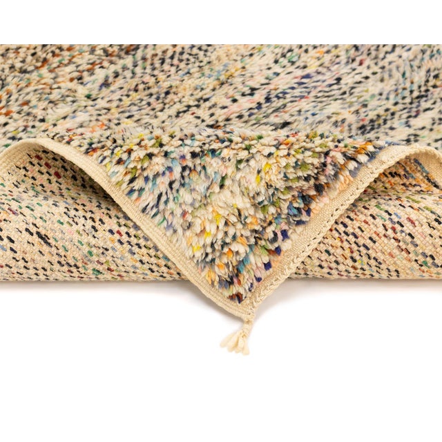 A small-scale rug with big graphic personality — a dense, abstract collage of color rendered in a speckled, hand-knotted...