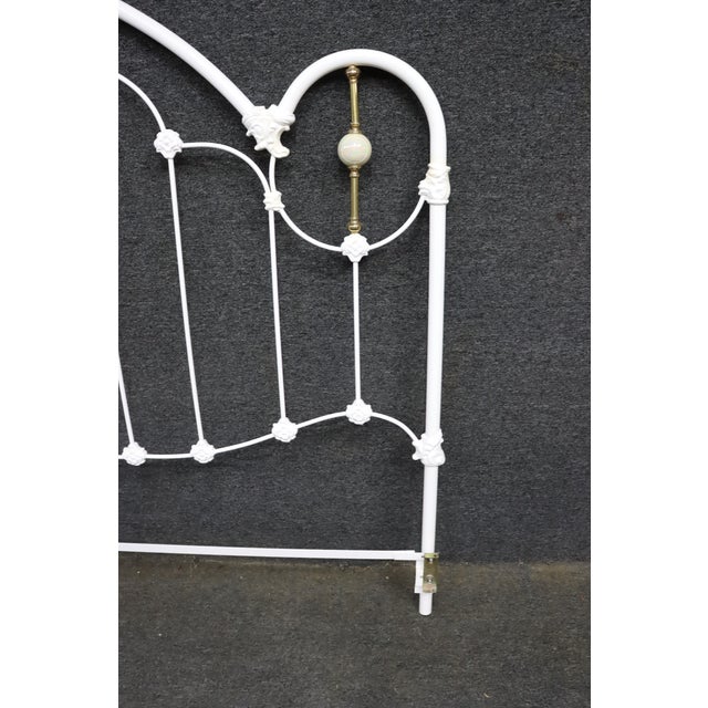 Victorian-style iron bed headboard finished in white, featuring an arched frame, decorative floral castings, and brass...