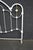 Victorian-style iron bed headboard finished in white, featuring an arched frame, decorative floral castings, and brass...
