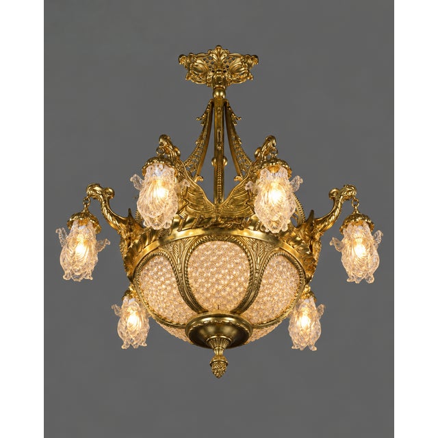 An impressive 1980 French Louis XVI-style chandelier, beautifully crafted in gilded bronze and decorated with sparkling...