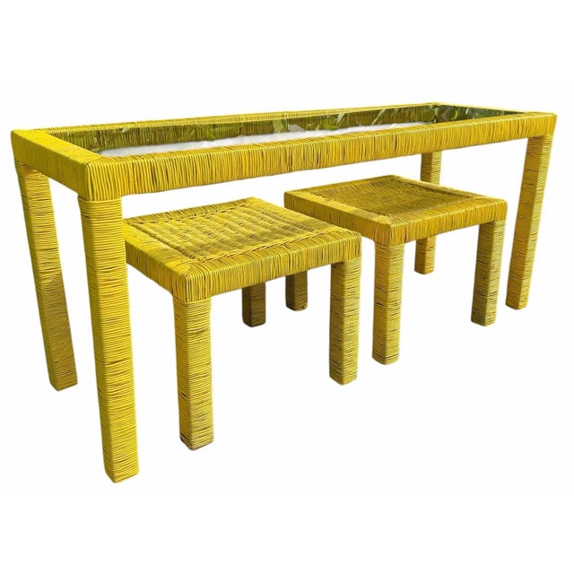 A distinctive three-piece vintage console table featuring a wood frame wrapped in rattan with two matching stools. Clean...
