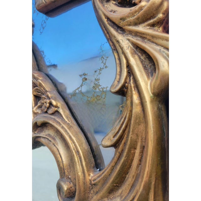 A beautiful vintage antique gold gilt shell motif topped wall mirror. The mirror features beautiful antique side with a...