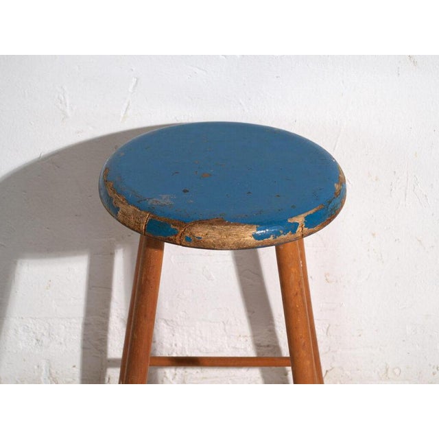 This antique wooden stool is a three-legged seat with a round seat and turned splayed legs joined by stretchers. It...