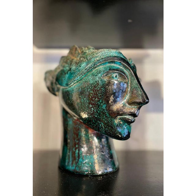 Sculpture depicting a head, crafted in glazed ceramic with shades ranging from black to green. A 1960s work. Measurements:...