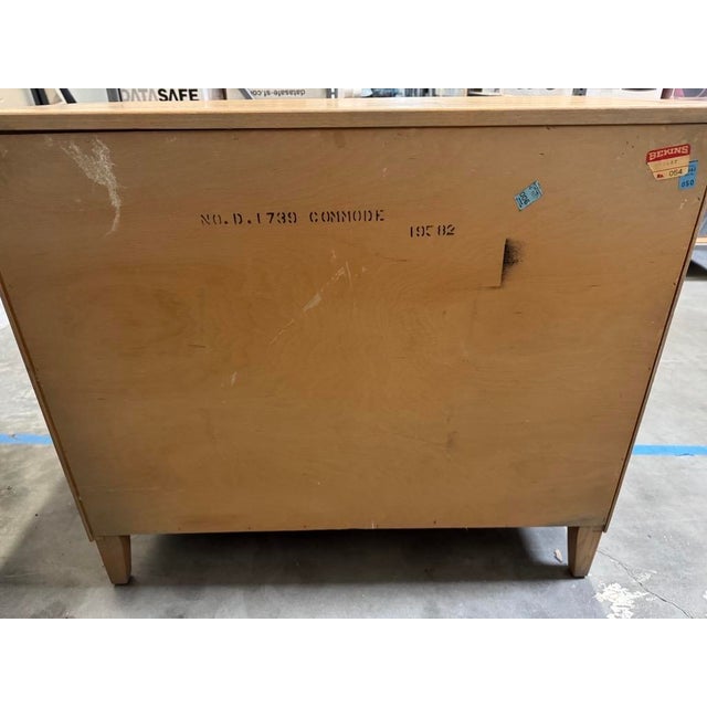 Elegant vintage French Provincial three drawer commode featuring a warm, lightwood-toned finish, gracefully scalloped...