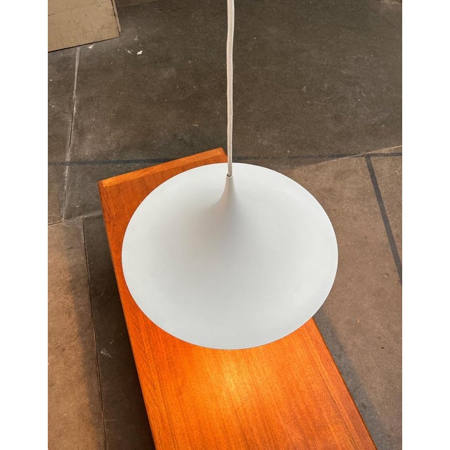 Classic semi pendant lamp in white. Elegant shape, narrow in profile. The entire shape of the luminaire runs together in a...