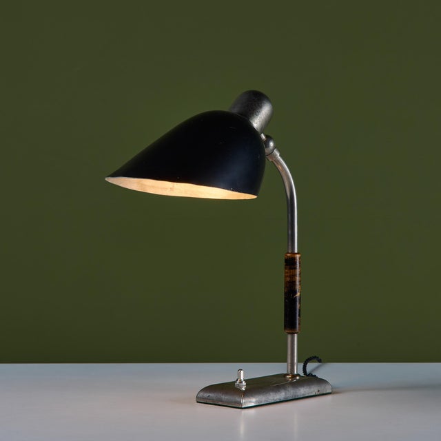 Industrial desk lamp with a black-enameled metal shade. The lamp sits on a rectangular steel base with a curved stem and...