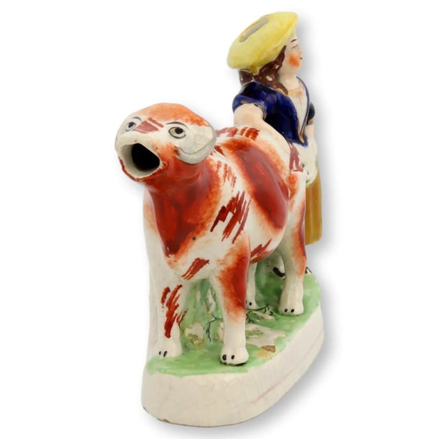 Antique Staffordshire cow and milkmaid cream pitcher. Cream is poured into hole in cow's back and dispensed through mouth....
