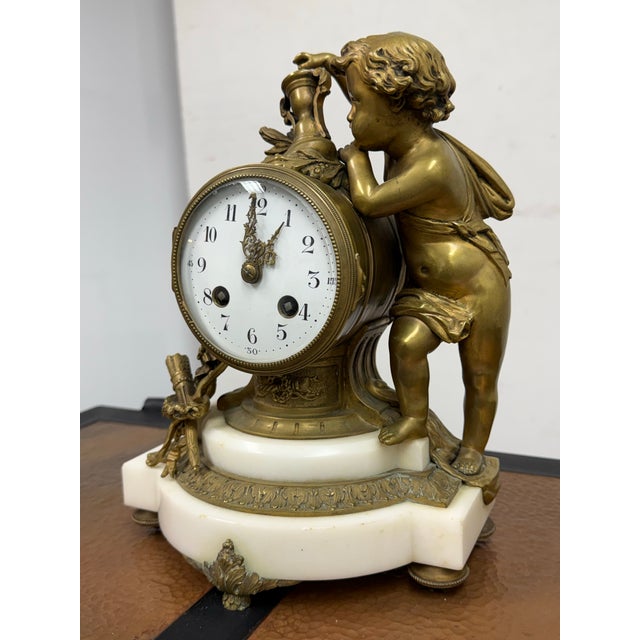 Design Plus Gallery presents a Bronze Figural Mantle Clock from the 19th Century. The mantel has a white marble base with...