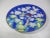 A decorative Asian porcelain plate with a gold trim. It is hand-painted with two blue and red pheasants resting on cherry...