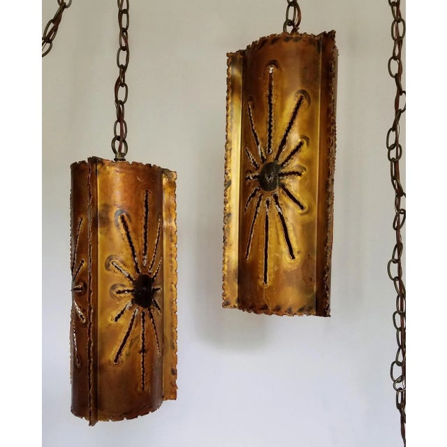 Monumental torch-cut metal tubes provide a striking presence in size and reach with super swag chain and large sunburst...