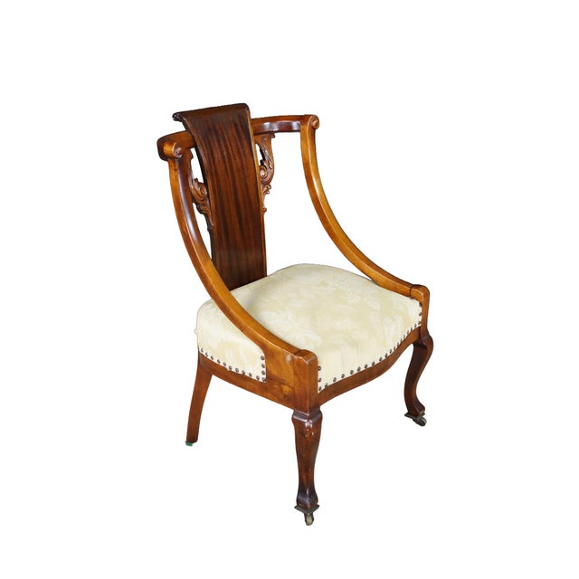 This exceptional 19th-century antique mahogany armchair masterfully combines the dramatic, sweeping lines of the...