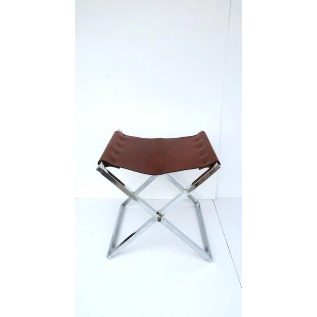 A well-made leather and chrome 'X' bench or stool, in the modern campaign style, circa 1970s. Stool/bench seat has a brown...