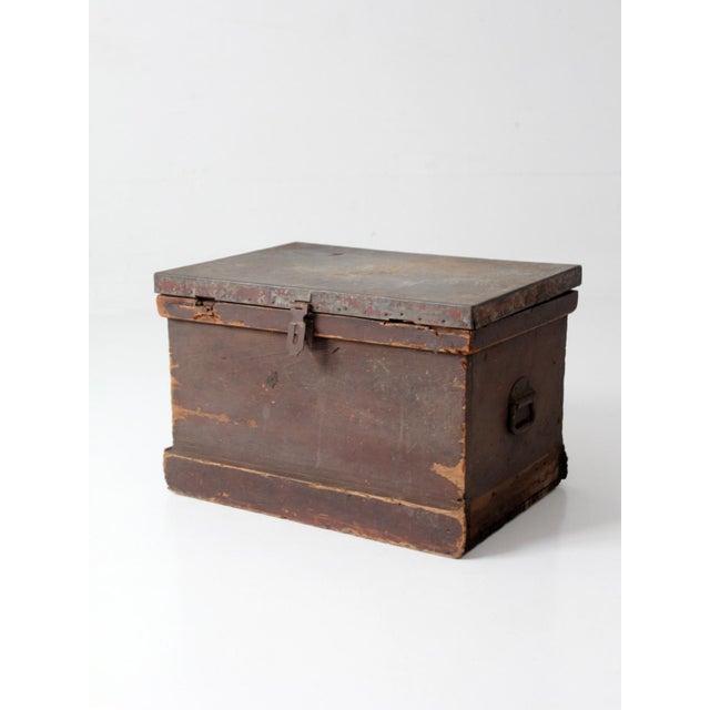 An antique railroad conductor’s box with a richly timeworn presence, featuring dark worn wood, a weathered metal-clad lid,...