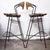 A pair of Arthur Umanoff mid century bar stools, for Raymor. They feature wood slat seats, iron frames with wicker wrapped...