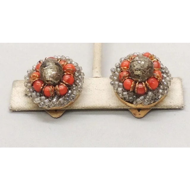 This is part of Chairish’s Costume Jewelry assortment. 1960s round goldtone grey round wavy glass center with smaller red...