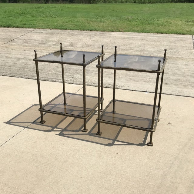 A pair of bronzed finish two tiered tables with glass tops. The frames with a gilt and black washed finish. By Italian...