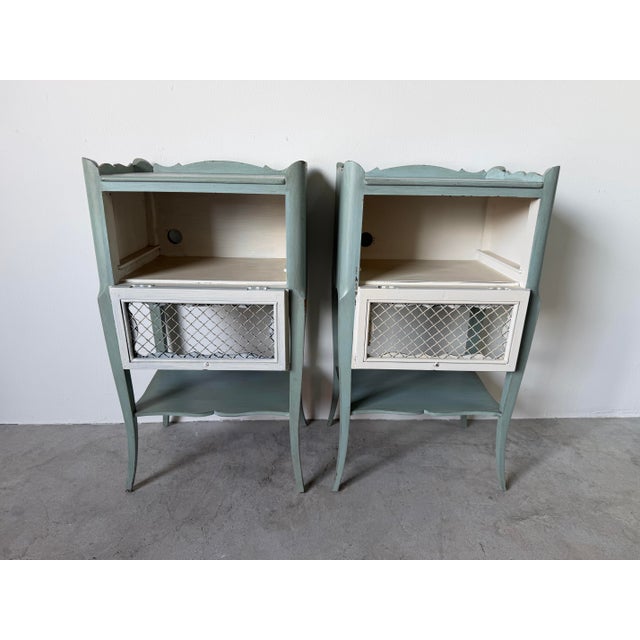 This elegant pair of 1960s vintage French Louis XV-style nightstands features a beautifully distressed soft sage green...