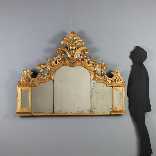 Carved and gilded wooden mantelpiece. The cymatium is pierced and carved with scrolls, leaves, flowers, and curls. The...