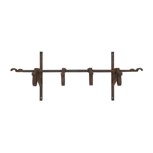 Vintage black wrought iron rustic or industrial style rack designed to be mounted on a wall, with vertical bars for...