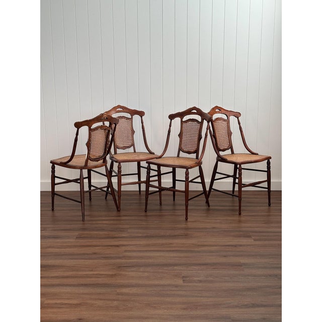 A set of four antique French dining chairs constructed from wood with cane seats and backs. Hand-turned legs and carved...