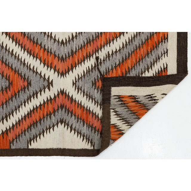 Elevate your interior space with this striking modern Navajo-style flatweave wool rug, featuring a high-impact geometric...