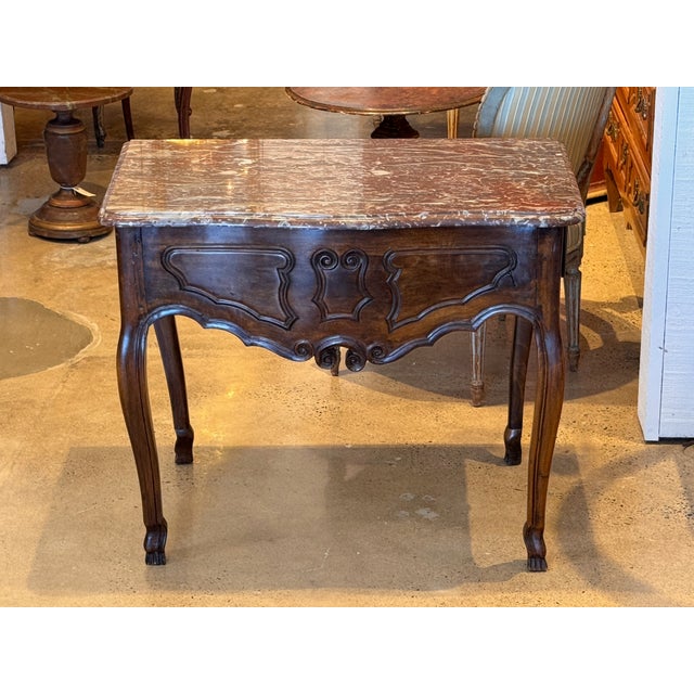 A 19th century French walnut console with a rectangular marble top over a side-mounted drawer, the drawer opening from the...