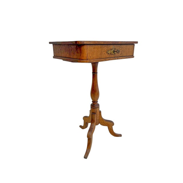 Elegant oak side table or sewing table from the early 20th century. The wood has a beautiful warm color, the table has...