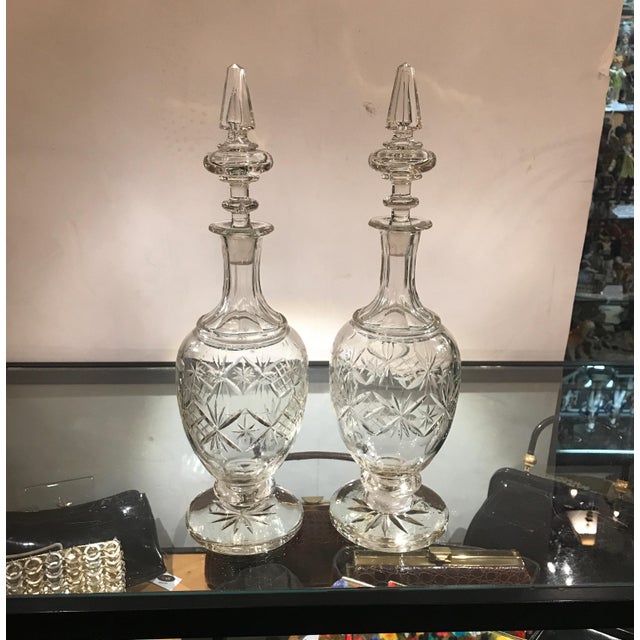 A pair of 19th century European cut glass decanters with spire stoppers. The speared panel cut tops with bulbous cut glass...