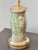 A vase-form glass table lamp decorated with botanical flowers, foliage, and butterflies against a mottled silver-colored...