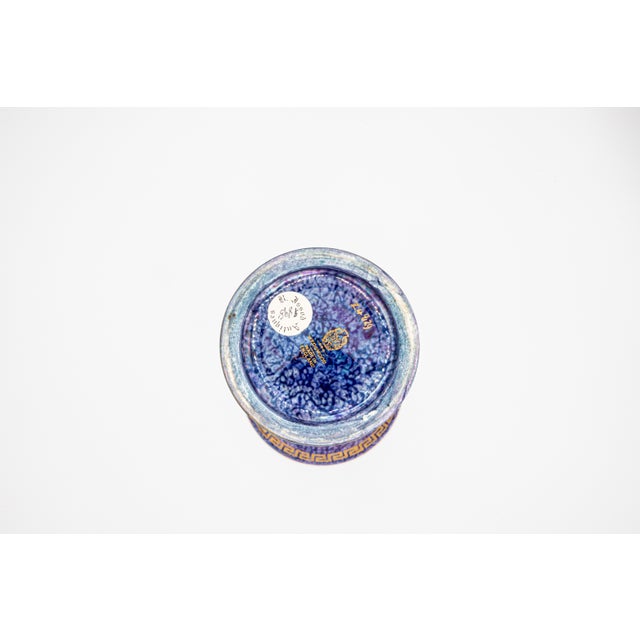 The exterior is finished in a mottled and streaked blue lustre glaze, with purple, blue, and violet tones interplaying in...