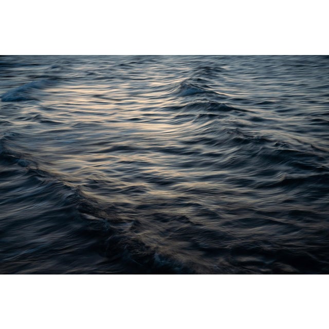 This photographic work captures the serene movement of waves, their undulating forms reflecting a soft interplay of light...