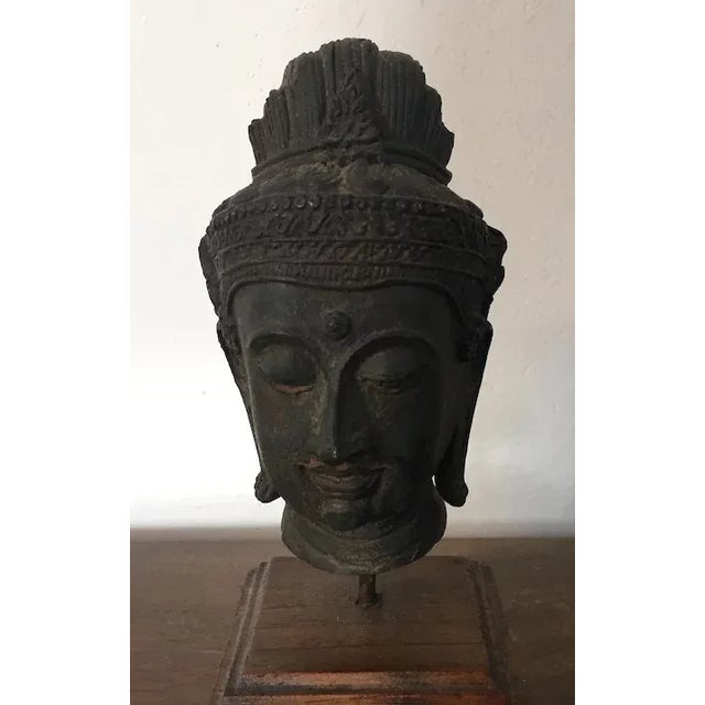 Antique bronze bust of Buddha mounted on a carved wood stand. Exceptional fine casting with verdigris patination. Measures...