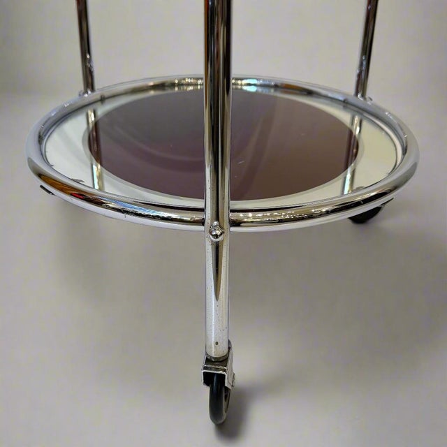 An Art Deco period two-tier mirrored serving cart from France circa 1930. The oval polished nickel frame with mirrored...