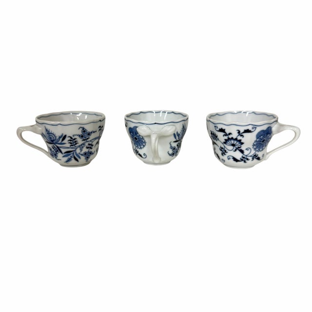 These porcelain tea cups feature a distinctive blue and white floral "onion" pattern, associated with the Blue Danube...